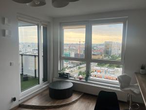 um quarto com três janelas com vista para uma cidade em Apartament SKYSCRAPPER z widokiem na panoramę Warszawy em Varsóvia