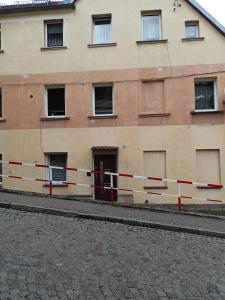 a building with a red and white fence in front of it at Apartament pod Chełmcem in Szczawno-Zdrój