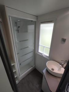 a white bathroom with a sink and a window at Camping la Grangeonne in Esparron-de-Verdon
