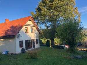 ein weißes Haus mit orangefarbenem Dach und einem Baum in der Unterkunft Dom w Rzeczce Góry Sowie in Rzeczka