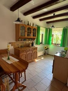 a kitchen with green curtains and a wooden table at Dom w Rzeczce Góry Sowie in Rzeczka