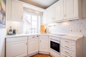 uma cozinha branca com armários brancos e uma janela em Haus-Munkhoog em Munkmarsch