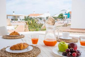 a table with food and orange juice and fruit at Villas Rymar in Cala en Bosc