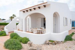 a white house with a table and chairs on a patio at Villas Rymar in Cala en Bosc