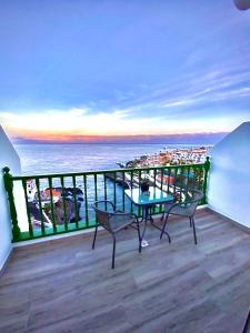 a balcony with a table and chairs and the ocean at Look and listen to the ocean like never before in Puerto de Santiago