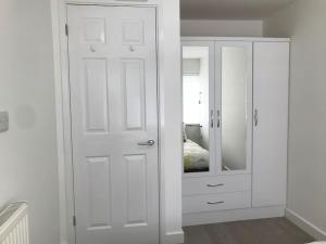 a bedroom with a white cabinet and a mirror at Dolly Cottage Colchester in Mile End