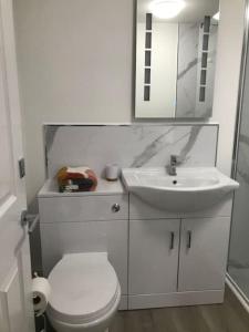 a white bathroom with a toilet and a sink at Dolly Cottage Colchester in Mile End