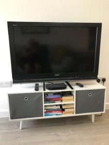 einen Flachbild-TV auf einem weißen Entertainment-Center in der Unterkunft Dolly Cottage Colchester in Mile End