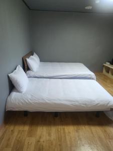two beds in a room with white sheets and pillows at Songwol Park in Sokcho +17 photos