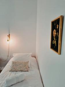 a white bed with a pillow and a picture on the wall at La Gare Soyons in Soyons