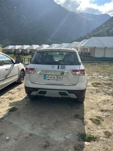 Bhrigu Camps في Jispa: سيارة بيضاء متوقفة في حقل بالقرب من الخيام