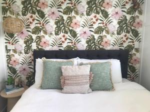 a bedroom with a bed with a floral wallpaper at Rustling Oaks NZ Tropical Tiny House in Tamahere