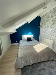 een slaapkamer met een groot bed met een blauwe muur bij Studio moderne en plein centre de Caen in Caen