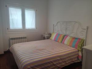 1 dormitorio con 1 cama con manta a rayas y 2 ventanas en Apartamento Ritort, en Camprodon