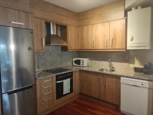 cocina con armarios de madera y nevera de acero inoxidable en Apartamento Ritort, en Camprodon