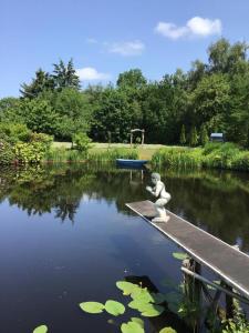 a statue of a teddy bear sitting on a dock in a pond at Moorgalerie in Edewecht