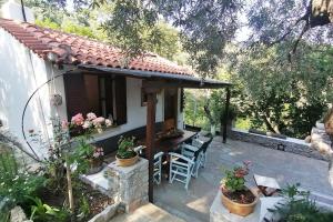 a patio with a table and chairs and a house at Vasilis' kalivi in Skiathos