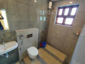 a bathroom with a white toilet and a sink at Nandhanam Holidays in Kannur