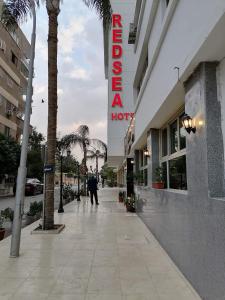 une personne marchant sur un trottoir devant un hôtel dans l'établissement RED SEA HOTEL - فندق ريد سى, à Suez