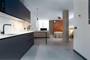 a kitchen with black cabinets and a bedroom at Calatrava by Alma Suites in Valencia