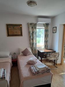 1 Schlafzimmer mit 2 Betten, einem Schreibtisch und einem Fenster in der Unterkunft Apartments Panonija in Novalja