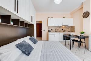 a bedroom with a large bed and a kitchen at Joker House Roma in 15 minuti Station Airport in Ciampino