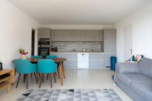 eine Küche und ein Wohnzimmer mit einem Tisch und blauen Stühlen in der Unterkunft Appartement avec terrasse vue mer Trouville sur mer in Trouville-sur-Mer