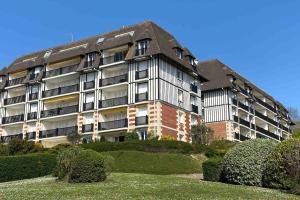 ein großes Apartmenthaus auf einem Hügel mit Büschen in der Unterkunft Appartement avec terrasse vue mer Trouville sur mer in Trouville-sur-Mer