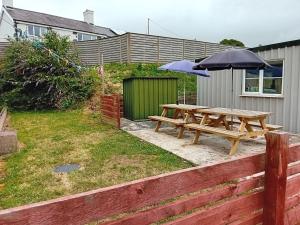 a picnic table and an umbrella in a yard at Criw Bach Static Caravan in Bryncroes