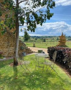 a table and chairs in the grass next to a tree at Luxury & comfort in the Cotswolds in Banbury +12 photos