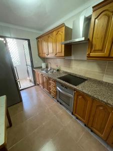 una cucina con armadi in legno e piano cottura. di Apartamento Jardines del Rocío a Torre del Mar