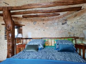 sypialnia z niebieskim łóżkiem w kamiennej ścianie w obiekcie La Tour de rêves w mieście Beaumont-la-Ronce