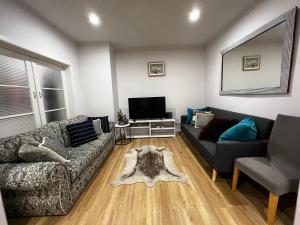 a living room with a couch and a tv at Charming House; Walk to Beach & Shops in Rosebud