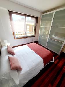 a bedroom with a bed with pillows and a window at Apartamento Pilartxo Zarautz in Zarautz