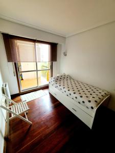a bedroom with a bed and a chair and a window at Apartamento Pilartxo Zarautz in Zarautz