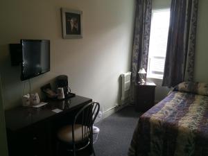 a hotel room with a bed and a desk with a television at Auberge Centre Ville in Saguenay