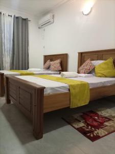 NYALI LUXURY APARTMENT في مومباسا: سريرين في غرفة نوم مع بطانيات ووسائد صفراء