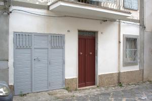 un edificio con due porte garage e una porta rossa di Appartamento ammobiliato a Pietraperzia