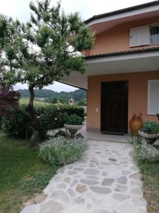 a house with a tree next to a walkway at Taoretto 1 in Serravalle delle Langhe
