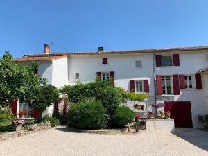 Biały dom z czerwonymi okiennicami i ogródkiem w obiekcie Chambres d'hôtes "Le Colombier" w mieście Venasque