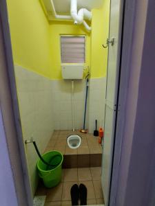 uma pequena casa de banho com WC e um balde verde em Homestay Warisan Violet em Malaca
