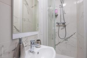 a bathroom with a sink and a shower with a mirror at Logement de standing à 18min de Paris La Défense in Colombes