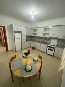 - une cuisine avec des placards blancs et une table fleurie dans l'établissement T. Bello Apartments, à Saranda