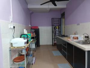 uma cozinha com paredes roxas, um balcão e um lavatório em Homestay Warisan Violet em Malaca