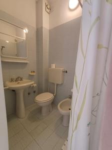 bagno bianco con servizi igienici e lavandino di Hotel Canarco a Viareggio