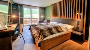 a bedroom with a bed and a desk and a window at Amber Ski-in/out Hotel & Spa in Saas-Fee