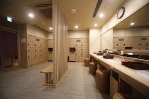 a large bathroom with sinks and a clock on the wall at Dormy Inn Oita in Oita