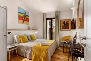 Un dormitorio con una cama con sábanas amarillas y una mesa. en FlaViArt, en Olbia
