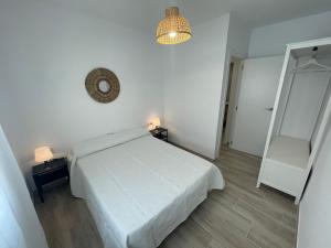 Dormitorio blanco con cama blanca y espejo en NUEVO, con vistas laterales al mar y a 60 metros de la playa, en Cullera