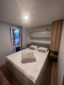 Schlafzimmer mit einem Bett mit weißer Bettwäsche und einem Fenster in der Unterkunft Mobile House F&L in Biograd na Moru